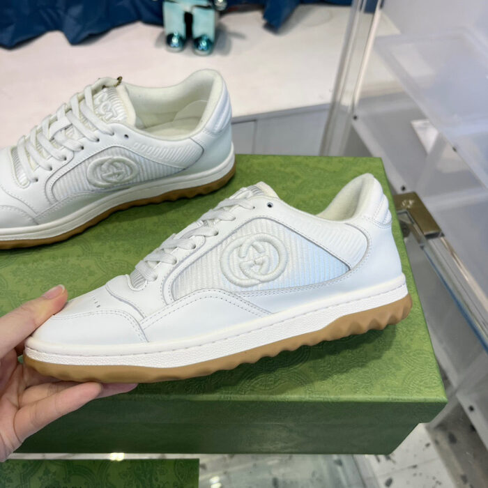 Scarpe sportive bianche di alta qualità su pedestale verde in boutique elegante.