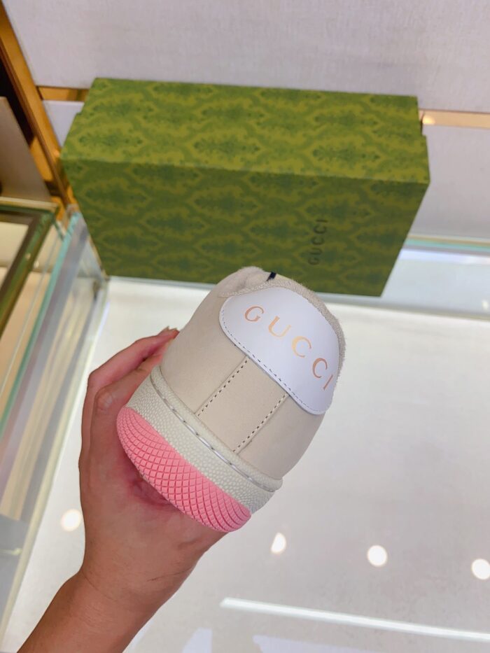 Sneaker beige con suola rosa e logo GIGO in primo piano, confezione elegante sullo sfondo.