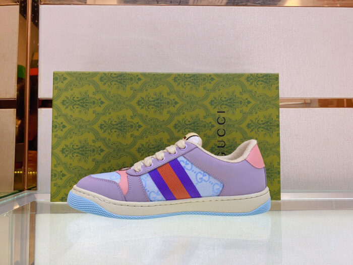 Sneaker Gucci color pastello su superficie lucida, design elegante e dettagli artigianali di alta qualità.