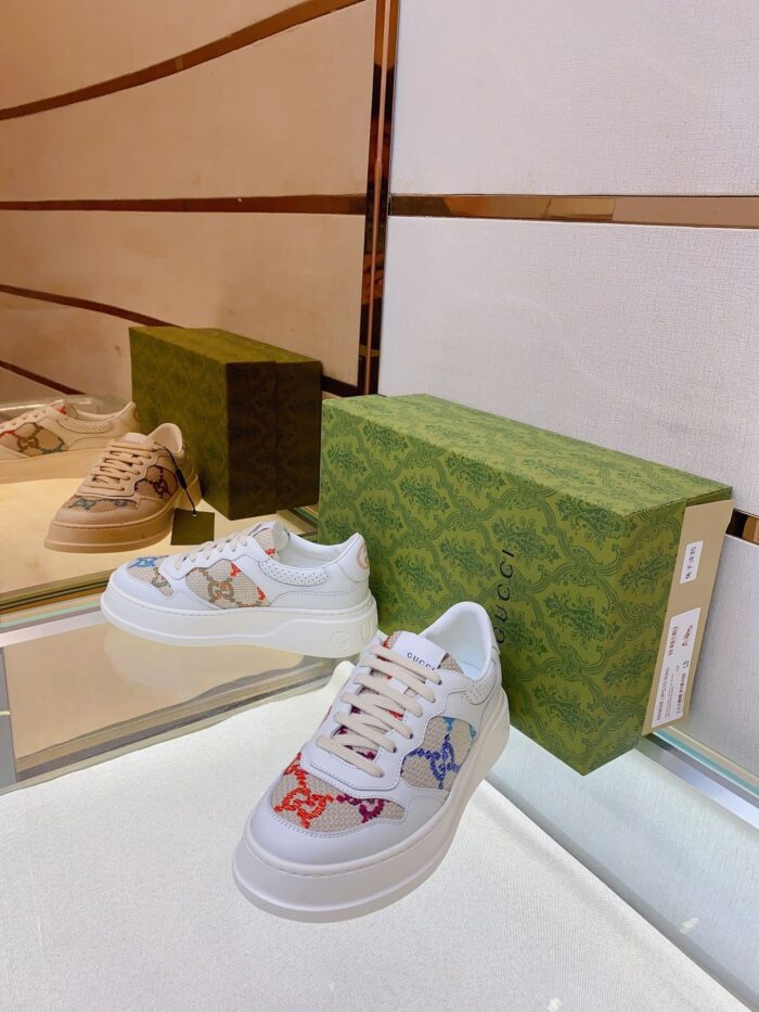 Sneakers di lusso con dettagli colorati, packaging elegante e stile contemporaneo su superficie riflettente.