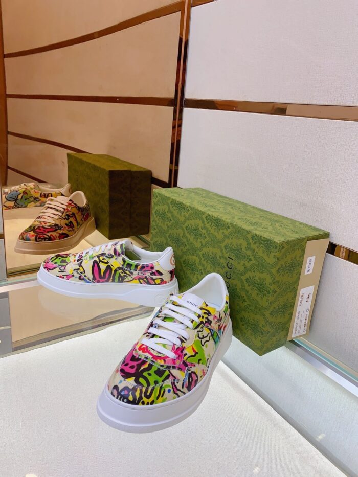 Sneaker artistica colorata su superficie riflettente con scatola verde, stile moderno e originale.