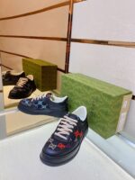 Sneaker blu elegante con dettagli colorati, su superficie riflettente, con scatola verde premium.