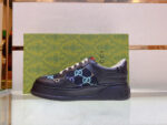 Sneakers Gucci nere con monogramma blu, su elegante packaging verde di lusso.