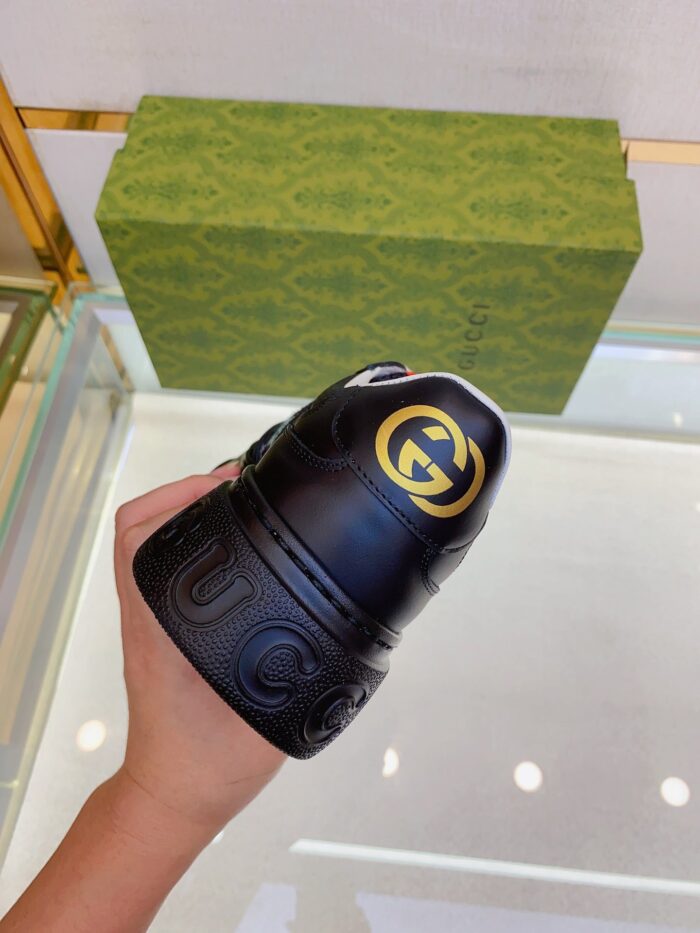 Sneaker Gucci nera in pelle con logo dorato, elegante e di lusso, in mano.