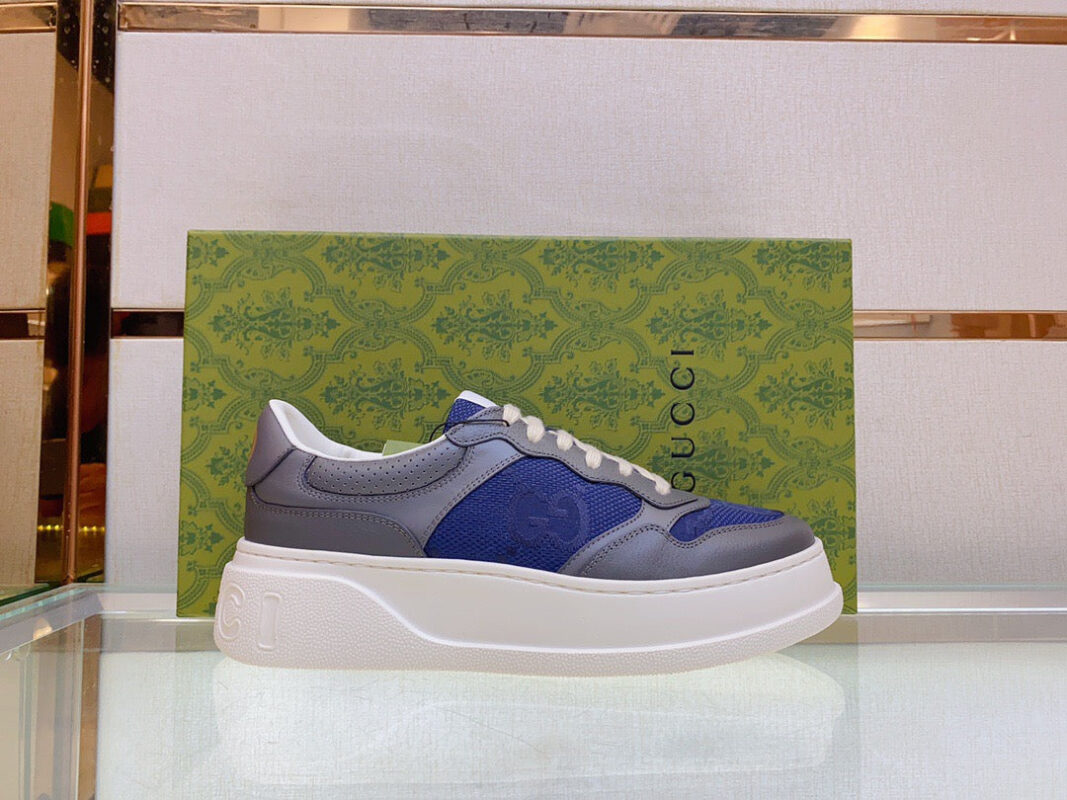 Scarpe sneakers di lusso in pelle con dettagli moderni su superficie di vetro riflettente.
