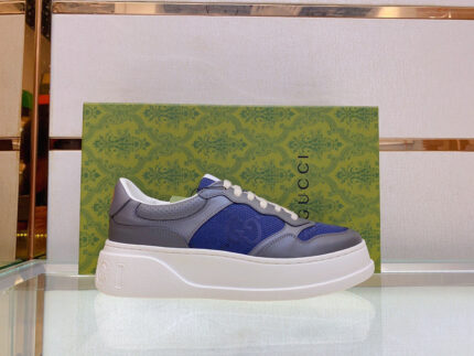 Scarpe sneakers di lusso in pelle con dettagli moderni su superficie di vetro riflettente.