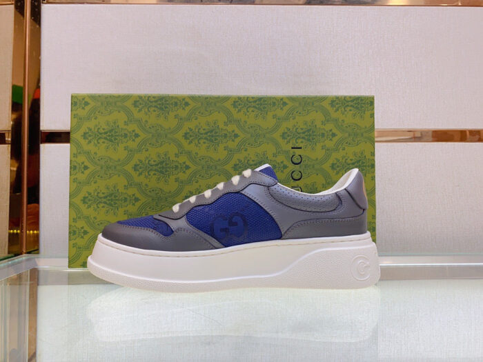 Sneaker Gucci moderna con logo iconico, su superficie lucida, con scatola elegante e design di lusso.