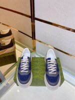 Sneakers blu e bianche su pedestal verde con riflesso, stile moderno e elegante.