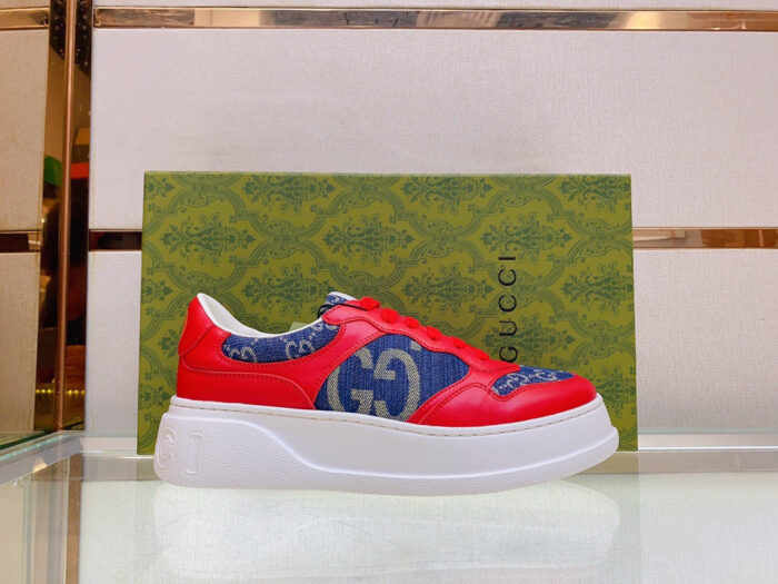 Sneaker Gucci rossa e blu con logo, su scatola elegante di lusso.