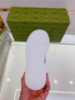 Sole di sneaker Gucci con logo, packaging di lusso su banco in negozio di alta moda.