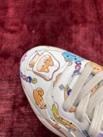 Sneaker bianca con illustrazioni divertenti e colori vivaci su fondo rosso morbido.