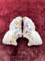 Sneakers colorate con motivi cartoon su sfondo rosso, stile moderno e giocoso.