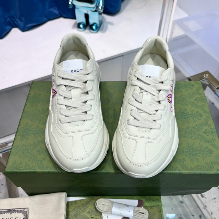 Sneakers Gucci in pelle beige su scatola verde, design minimalista e dettagli di lusso.