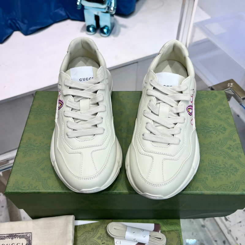 Sneakers Gucci in pelle beige su scatola verde, design minimalista e dettagli di lusso.