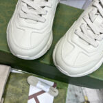 Scarpe da ginnastica beige di lusso su scatola verde con dettagli eleganti e rifiniture di qualità.