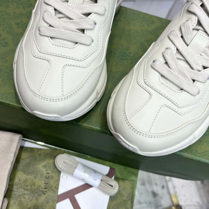 Scarpe da ginnastica beige di lusso su scatola verde con dettagli eleganti e rifiniture di qualità.