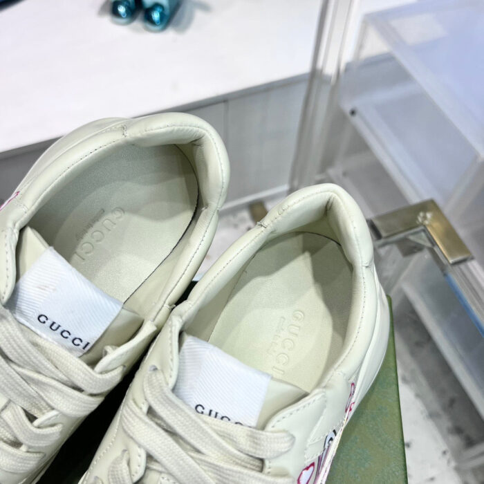 Scarpe Gucci in pelle bianca di lusso, stile moderno e dettagli artistici.