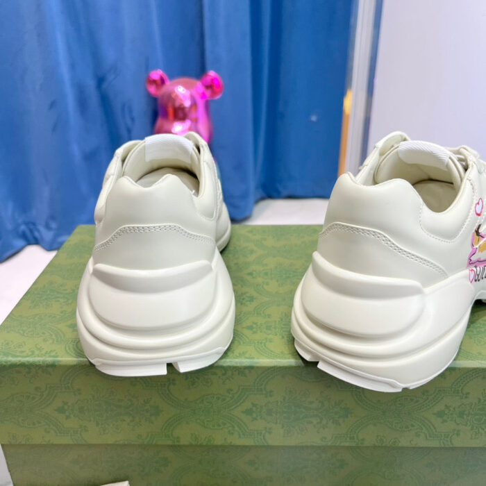 Scarpe sportive bianche su scatola verde con sfondo blu e decorazioni colorate.