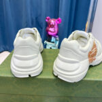 Sneakers moderne con dettagli lucidi e orsetto rosa giocoso sullo sfondo, stile streetwear.