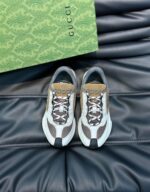 Sneakers Gucci di lusso in tonalità neutre, presentate su una superficie in pelle nera elegante.