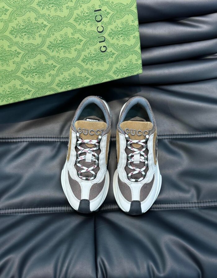 Sneakers Gucci di lusso in tonalità neutre, presentate su una superficie in pelle nera elegante.