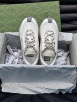 Sneakers di lusso con lacci elastici e packaging elegante su superficie nera.