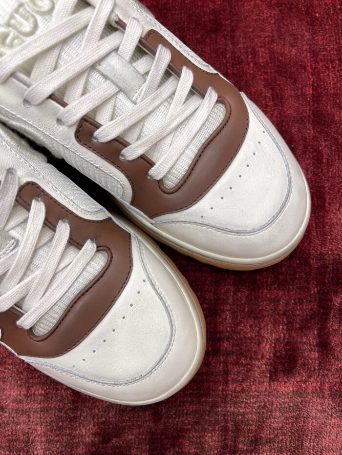 Sneakers bianche e marroni eleganti su sfondo rosso, stile moderno e comfort sportivo.