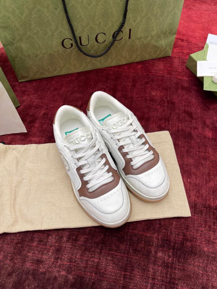 Sneakers Gucci bianche con dettagli marroni e shopping bag elegante, stile sportivo di lusso.