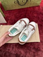 Scarpe Gucci sneakers bianche e marroni su sfondo rosso, elegante e di lusso.