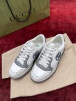 Sneakers di lusso Gucci in bianco e grigio, con logo distintivo e stile moderno.