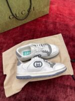 Scarpe Gucci eleganti su superficie rossa, con dust bag e shopping bag verde in evidenza.