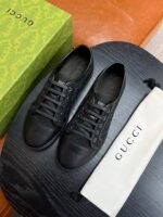 Scarpe sportive nere di lusso Gucci con dust bag e packaging elegante su superficie in legno.