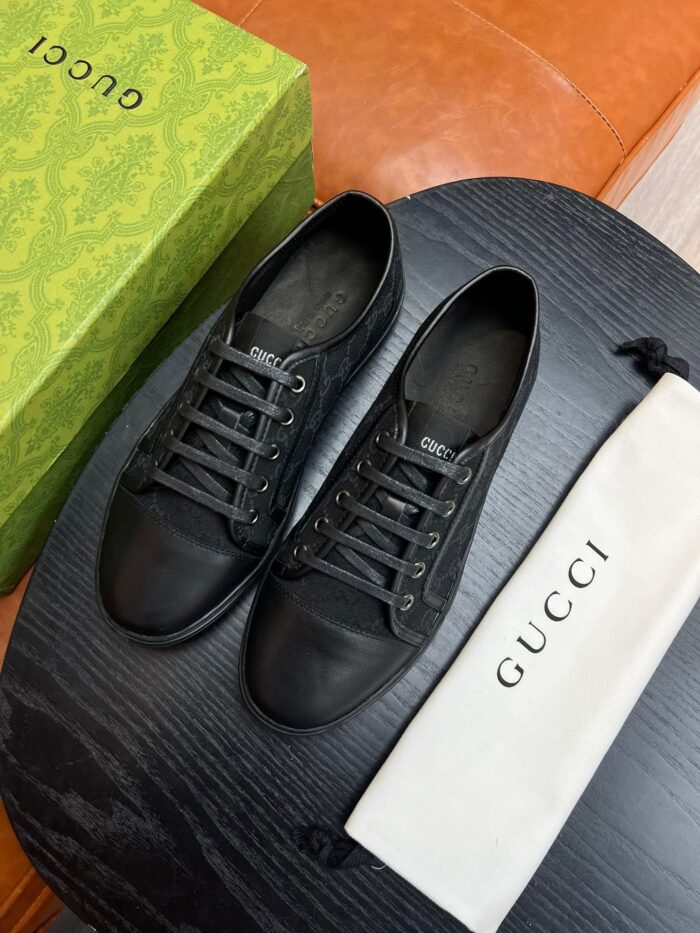Scarpe sportive nere di lusso Gucci con dust bag e packaging elegante su superficie in legno.