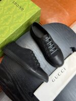 Sneaker Gucci nere di lusso su superficie in legno con custodia bianca e box verde elegante.