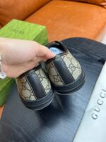 Scarpe Gucci monogramma con packaging colorato e stile elegante, mostrato a mano su sfondo accogliente.