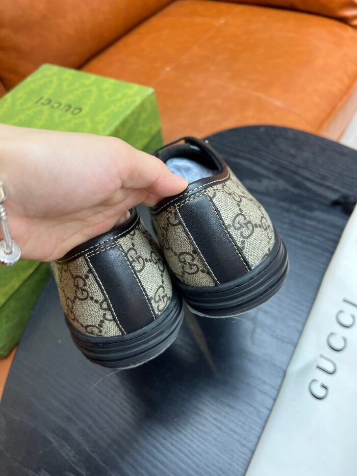 Scarpe Gucci monogramma con packaging colorato e stile elegante, mostrato a mano su sfondo accogliente.
