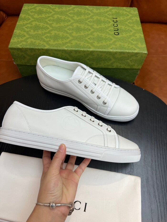 Sneakers bianche di lusso con scatola verde elegante e dust bag beige.