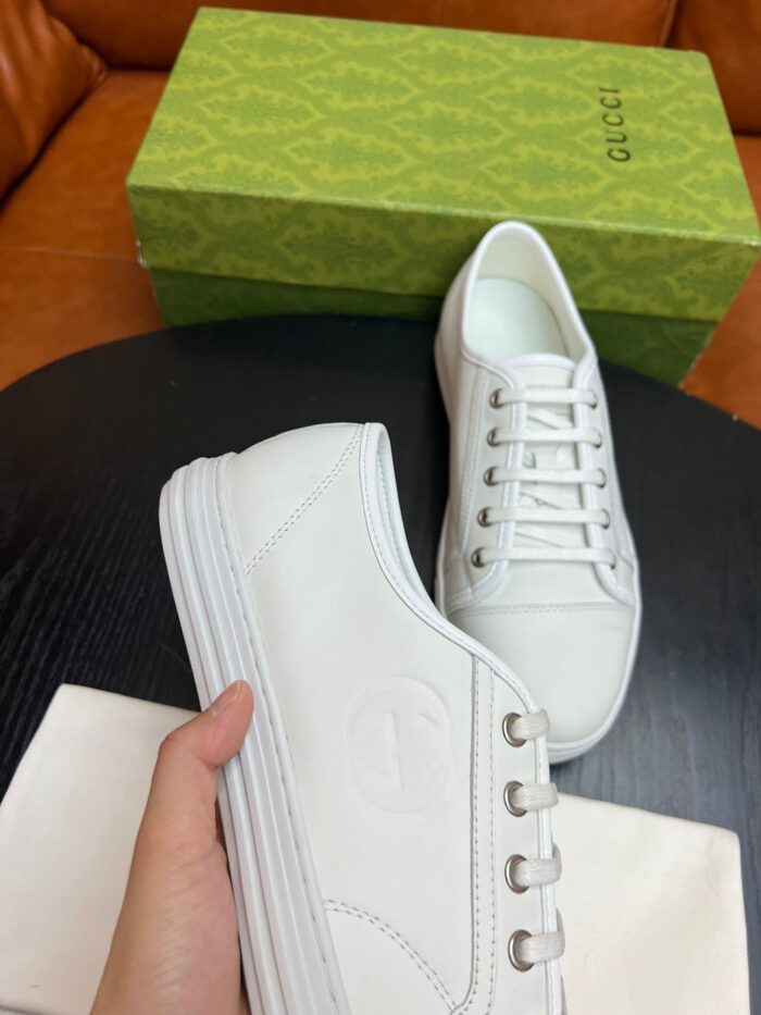 Sneakers bianche di lusso con packaging raffinato e design minimalista in pelle di alta qualità.