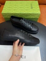 Sneaker Gucci nere di lusso con scatola verde elegante e dettagli moderni.