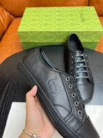Sneakers nere in pelle di lusso con scatola verde, stile minimalista e design sofisticato.
