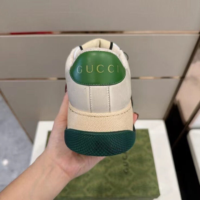 Sneaker Gucci in pelle bianca con dettagli verdi e logo in rilievo sul tallone.