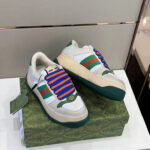 Sneakers bianche con dettagli verdi, rossi e lacci blu su scatola verde vibrante.
