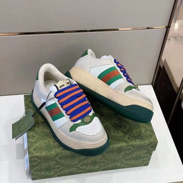 Sneakers bianche con dettagli verdi, rossi e lacci blu su scatola verde vibrante.