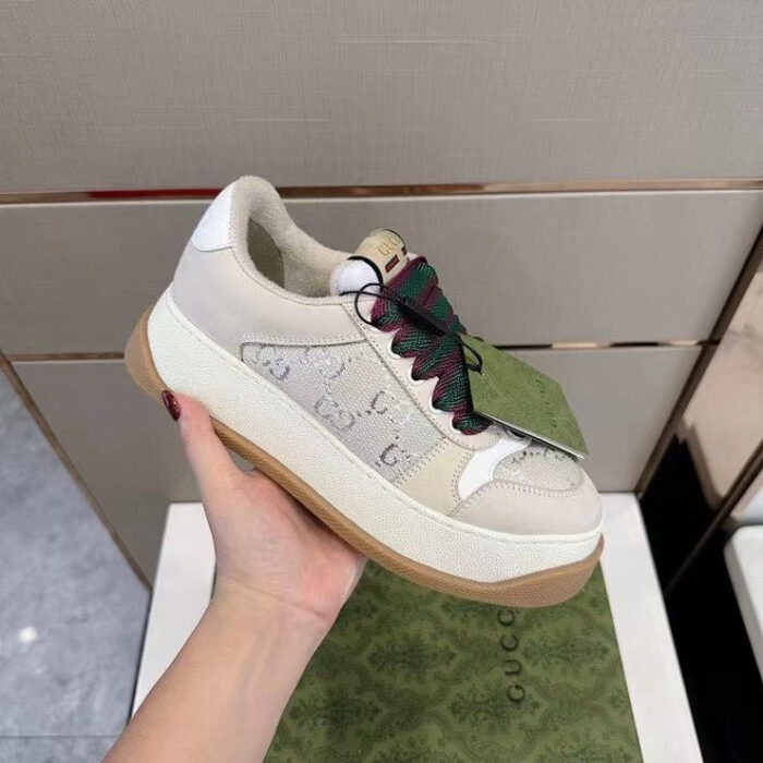 Sneaker Gucci beige con lacci verde rosso, stile casual e sofisticato, su suola in legno chiaro.