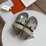 Sandali di lusso con logo H, stile moderno, su tavolo bianco, packaging elegante e design minimalista.