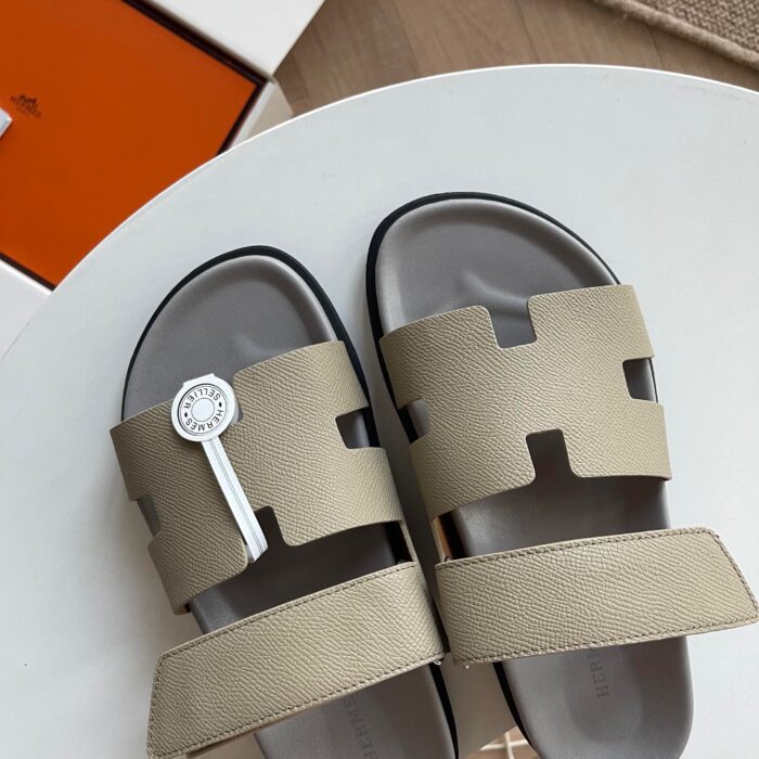Sandali beige moderni con straps a taglio e dettaglio di lusso su tavolo bianco.