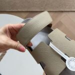 Sandalo Hermès beige in pelle, design elegante e moderno, con logo distintivo su rivestimento.