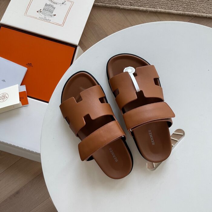 Sandali slip-on marroni di lusso con design moderno e dettagli eleganti, ideali per l’estate.