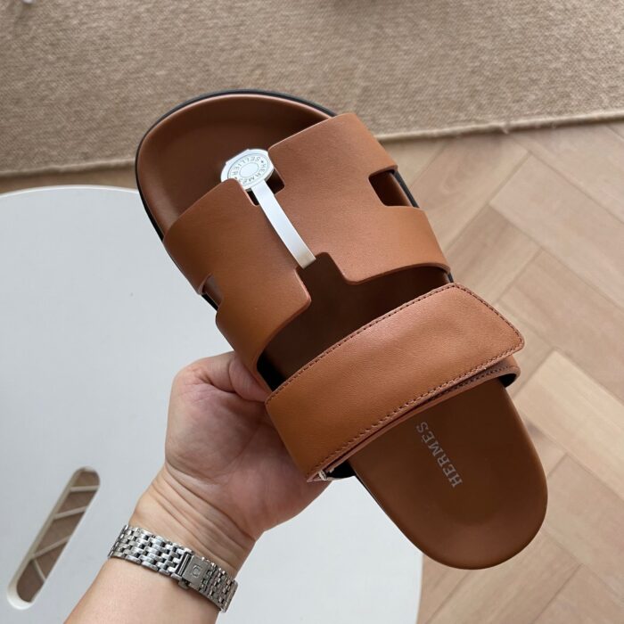 Sandalo in pelle marrone con dettaglio bianco, design elegante e stile casual moderno.