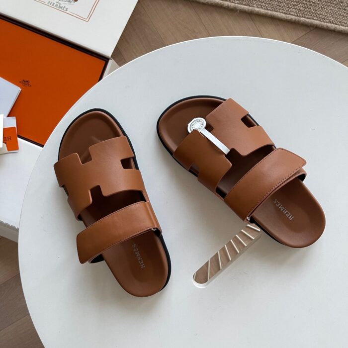 Sandali in pelle marrone di lusso su tavolo bianco, design elegante e modern.